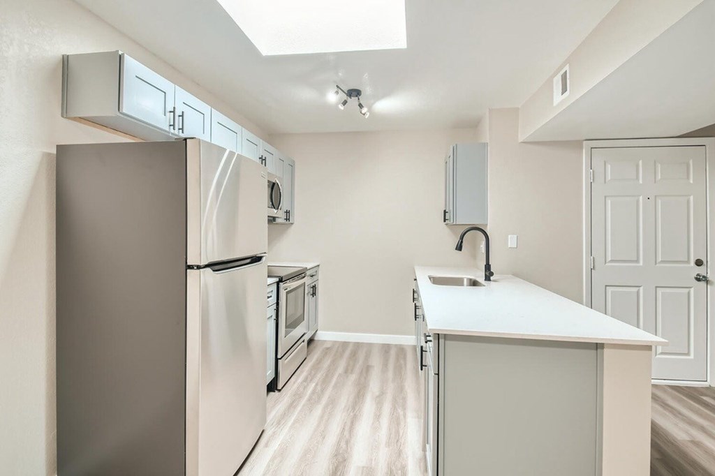 A kitchen with a refrigerator, microwave, oven, and sink.