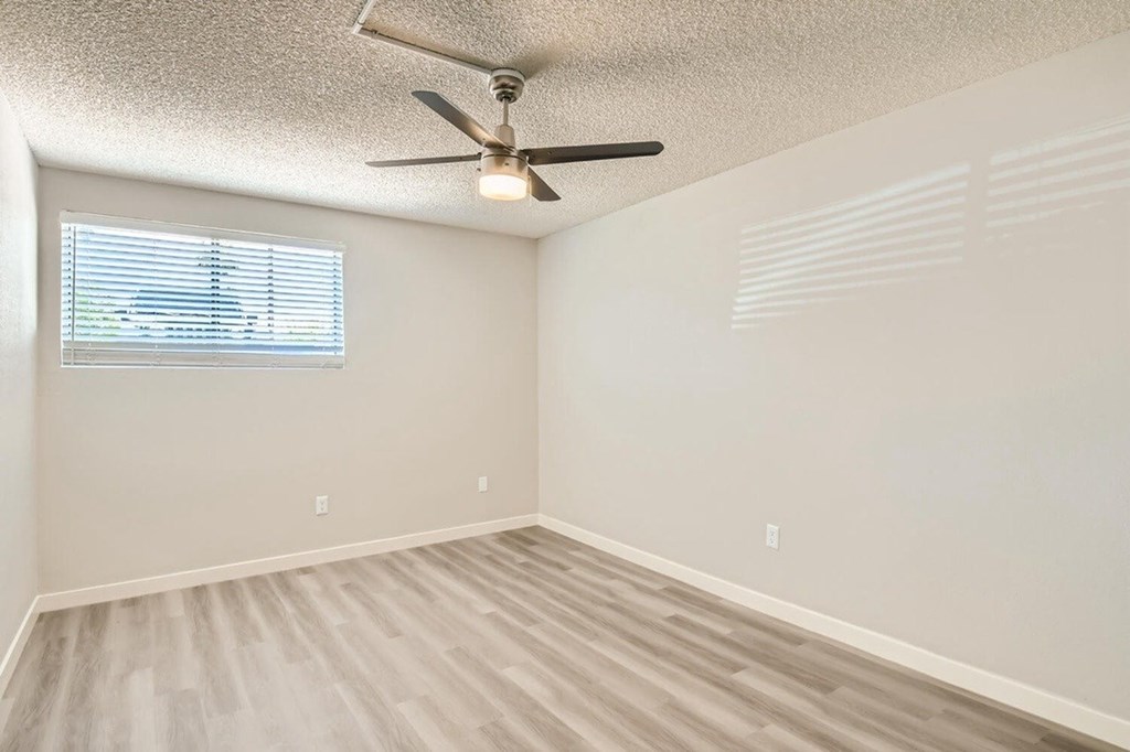A room with a ceiling fan and a window with blinds.