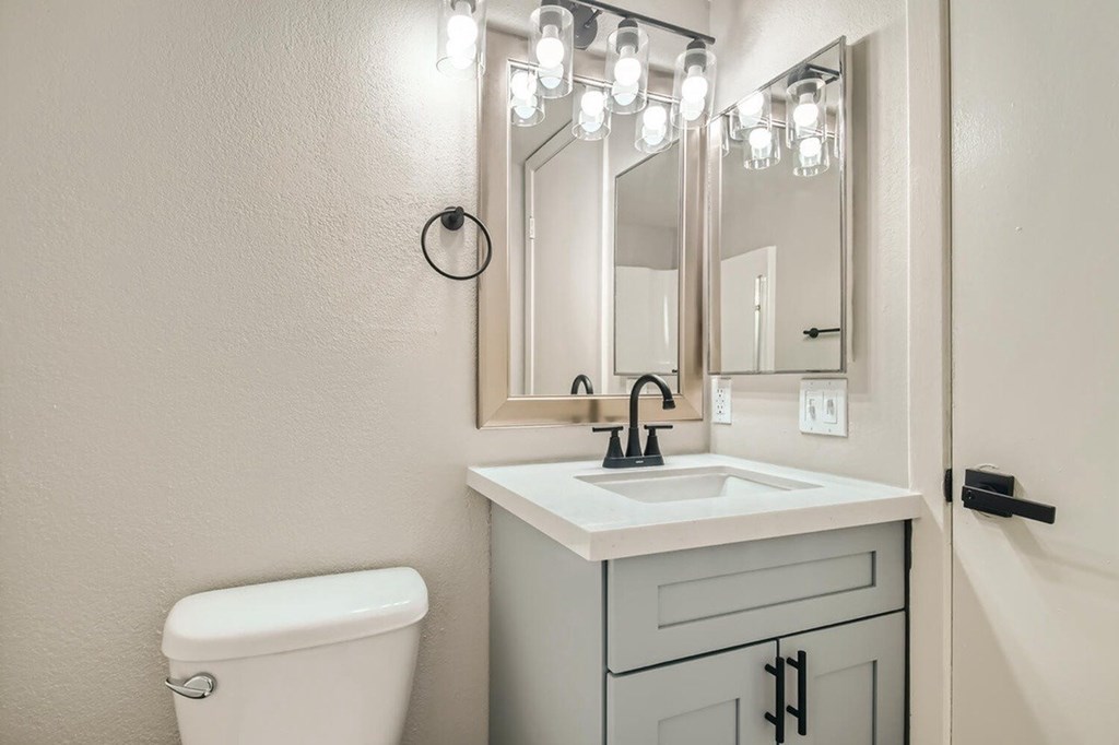 A bathroom with a white toilet, sink, and mirror.