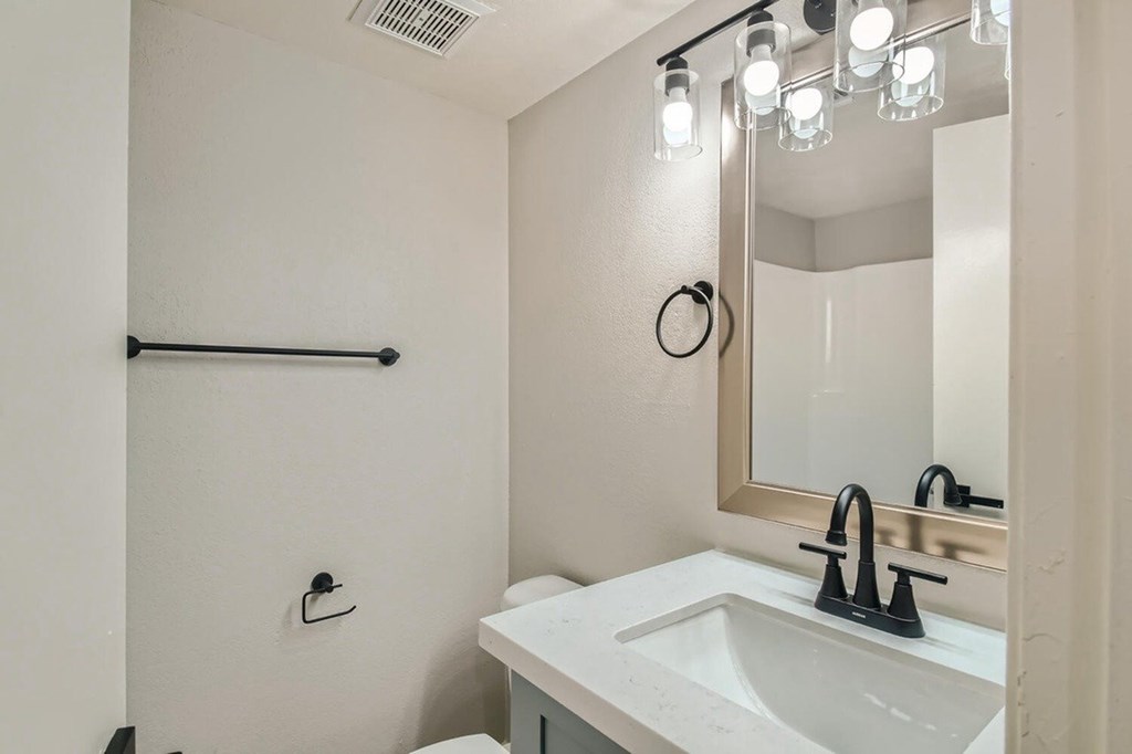A white bathroom with a sink and mirror.