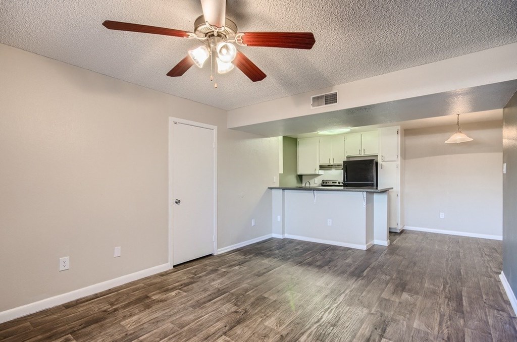 A room with a ceiling fan and wooden flooring.