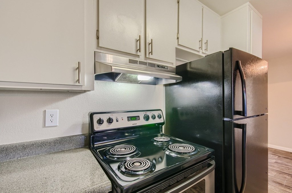 A black stove in a kitchen with white cabinets.