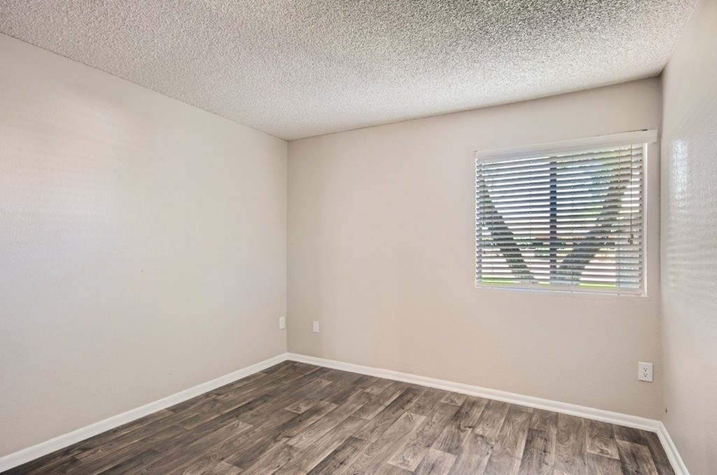 A room with wooden flooring and a window with blinds.