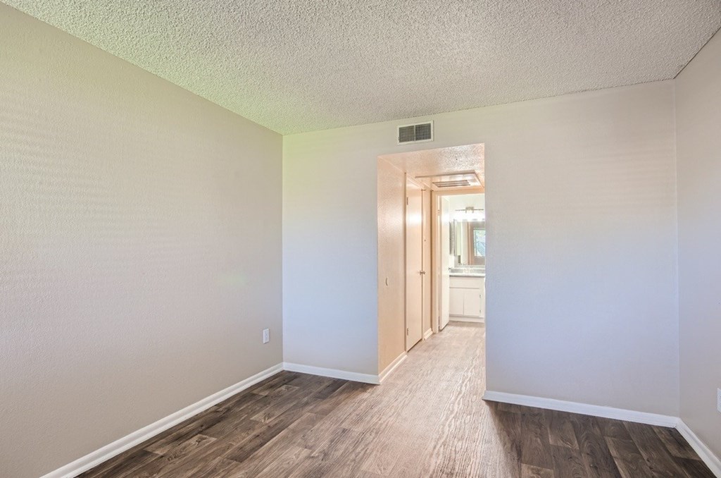 A room with wooden flooring and a doorway leading to another room.