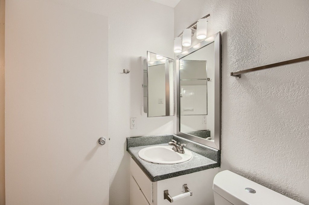 A bathroom with a sink, mirror, and toilet.