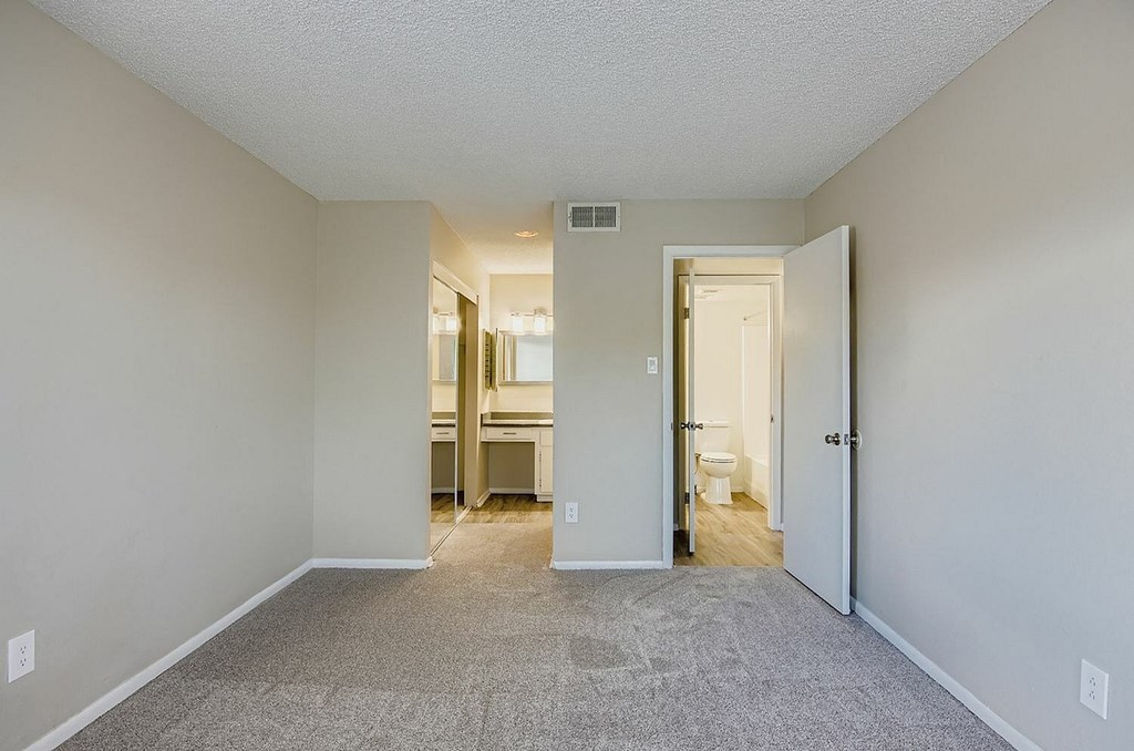 A bathroom with a toilet, sink, mirror, and lights.