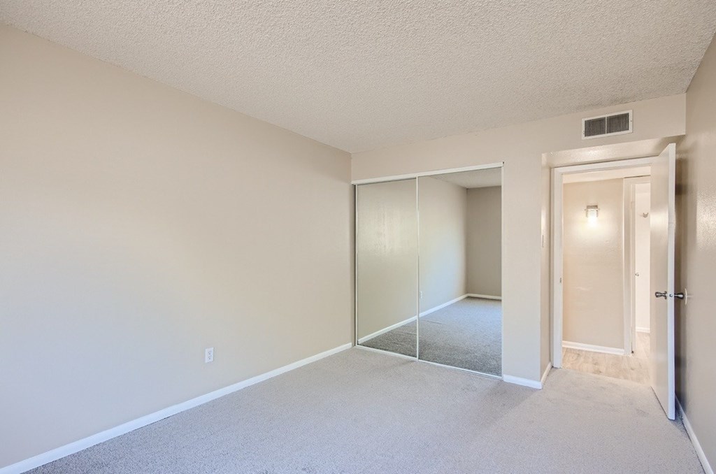 A room with a white door and a carpeted floor.