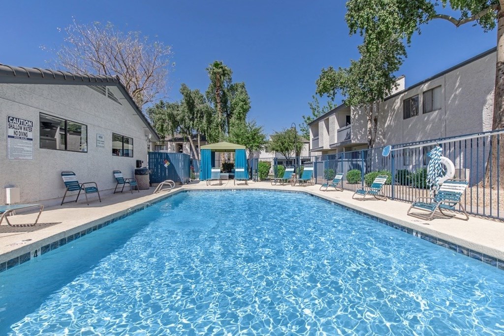 A swimming pool surrounded by chairs and a fence.