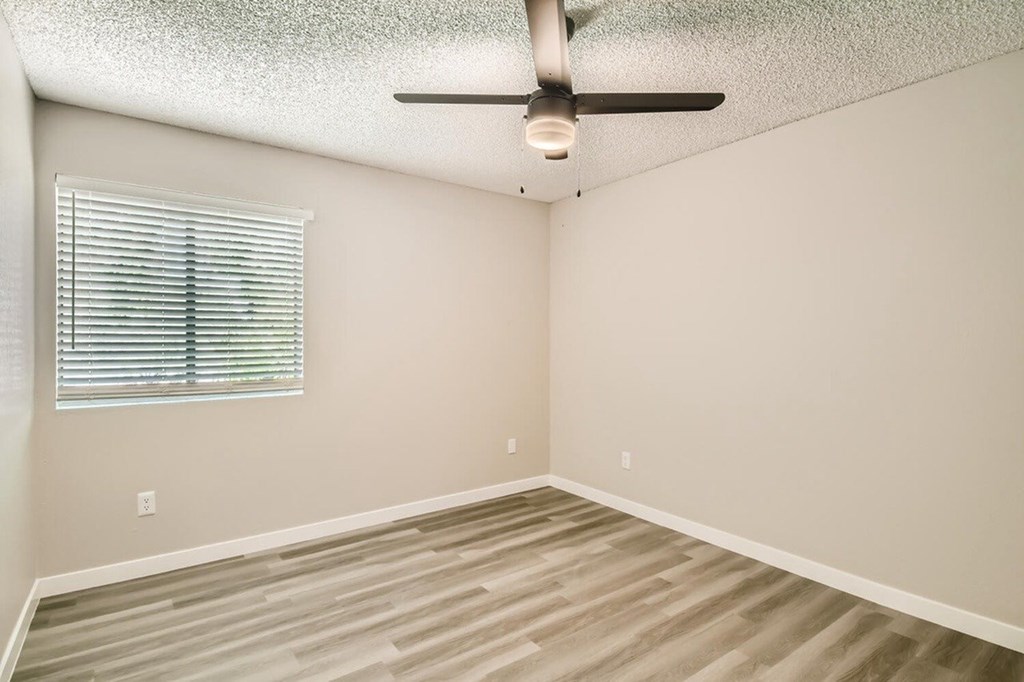 A room with a ceiling fan and a window with blinds.