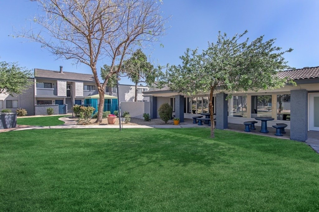 A grassy area in front of a building with a tree in the middle.
