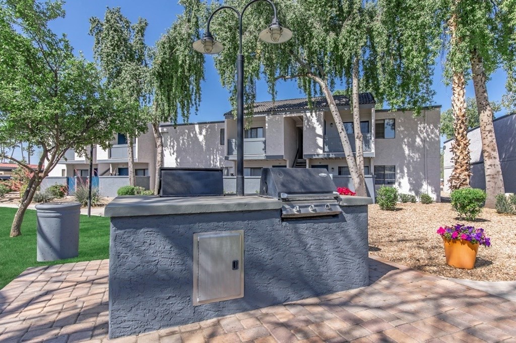 A grey concrete structure with a door and a window is surrounded by trees and plants.