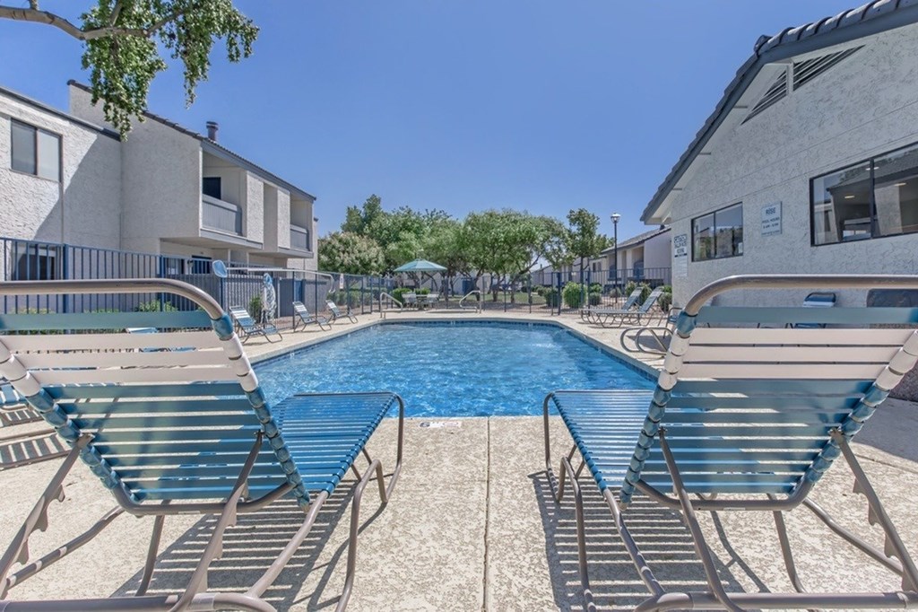 A swimming pool with lounge chairs and a building in the background.