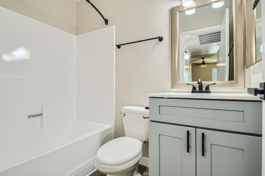 A white toilet sits next to a white bathtub in a bathroom.