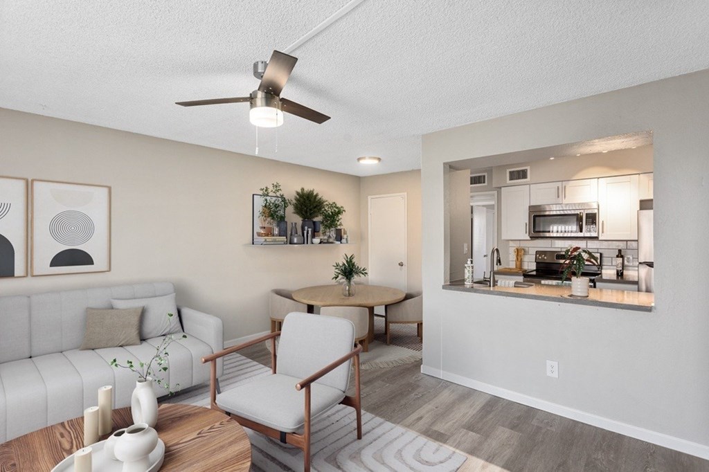 A living room with a white sofa, a wooden coffee table, and a ceiling fan.
