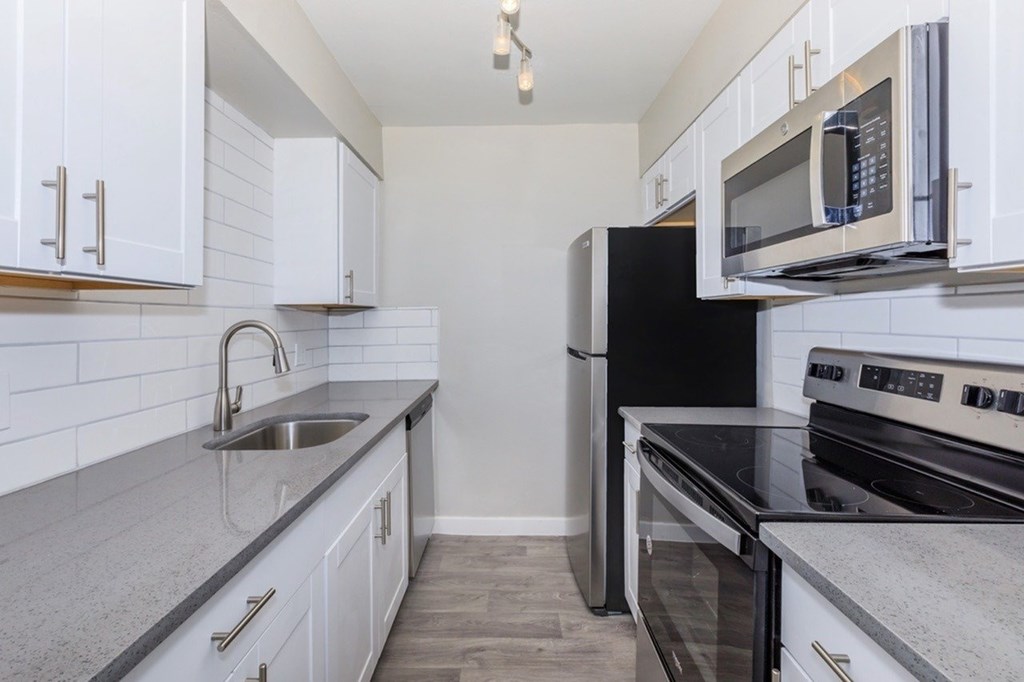 A kitchen with white cabinets and black appliances.
