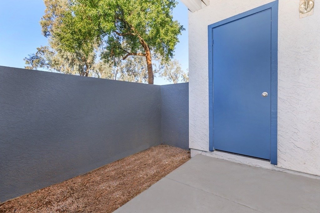 A blue door is on the right side of a white wall.