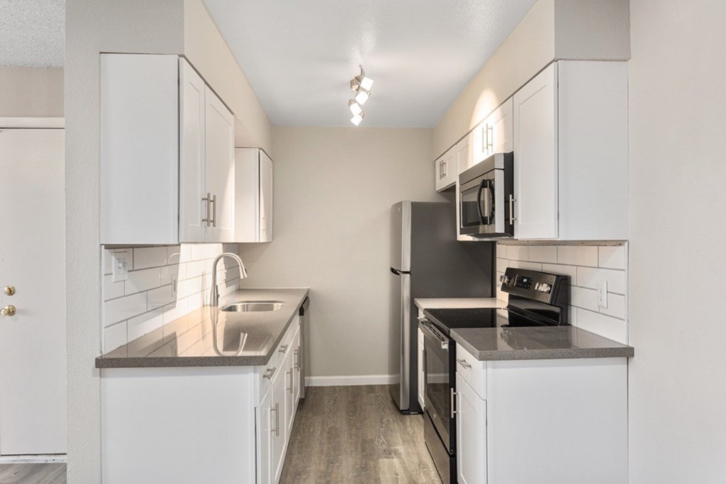 A kitchen with white cabinets and a black fridge.