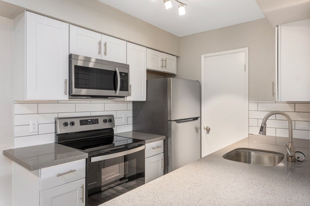 A kitchen with white cabinets and a black stove top oven.