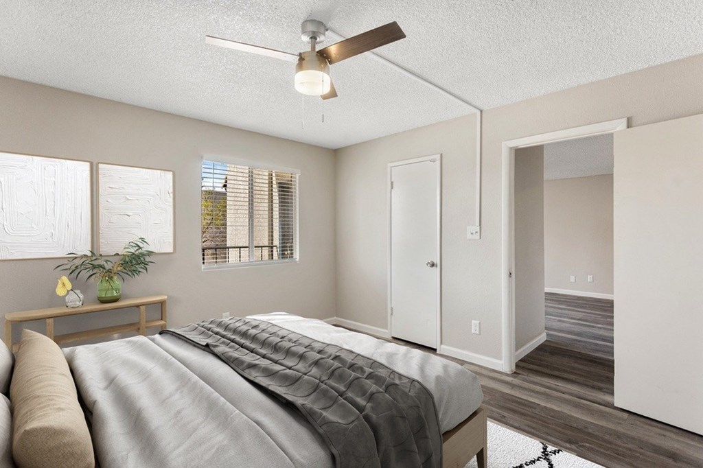 A bedroom with a bed, a ceiling fan, and a window with blinds.