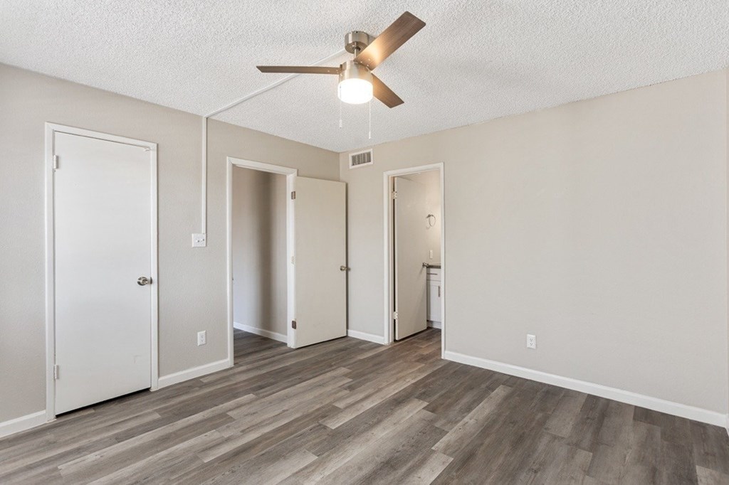 A room with a ceiling fan and wooden flooring.