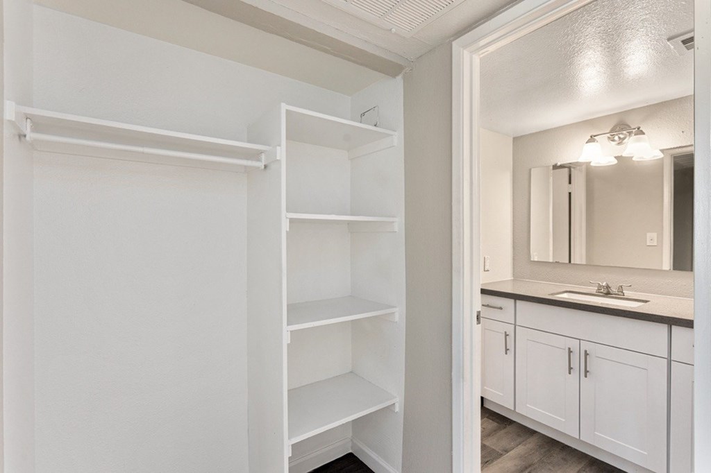 A white bathroom with a mirror and shelves.