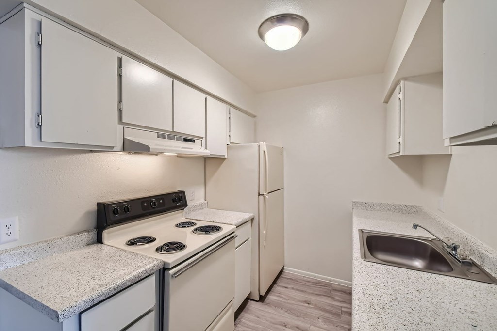 A kitchen with a stove, refrigerator, and sink.