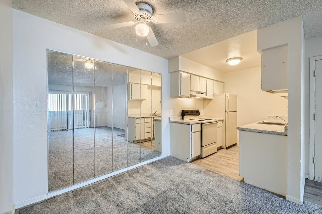 A kitchen with white appliances and a ceiling fan.