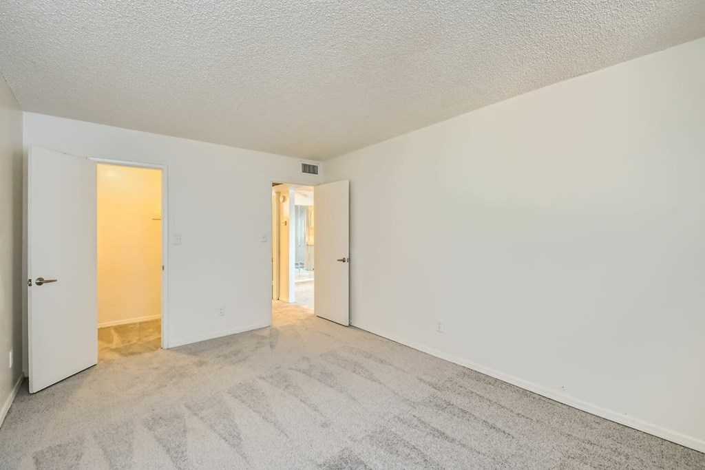 A room with a carpeted floor and two doors.