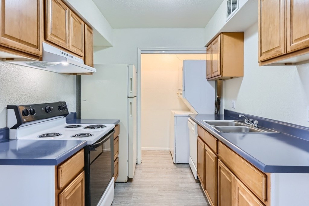 A kitchen with white appliances and wooden cabinets.