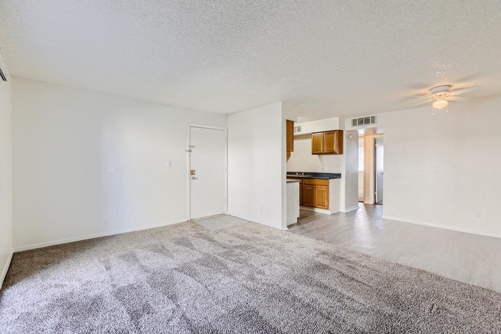 A spacious room with a carpeted floor and a ceiling fan.