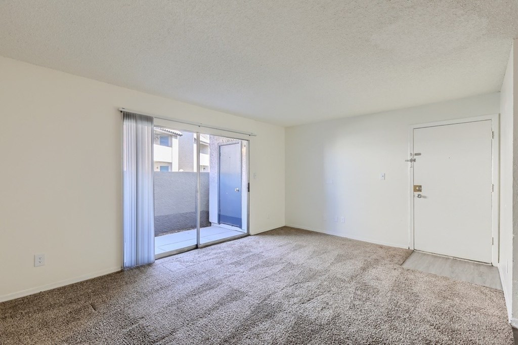 A room with a carpeted floor and a sliding glass door.