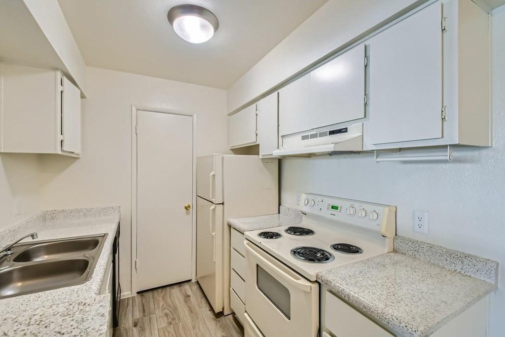 A kitchen with white cabinets and a stove top oven.