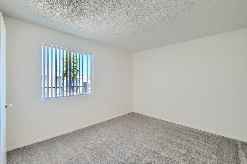 A room with a window and carpeted floor.