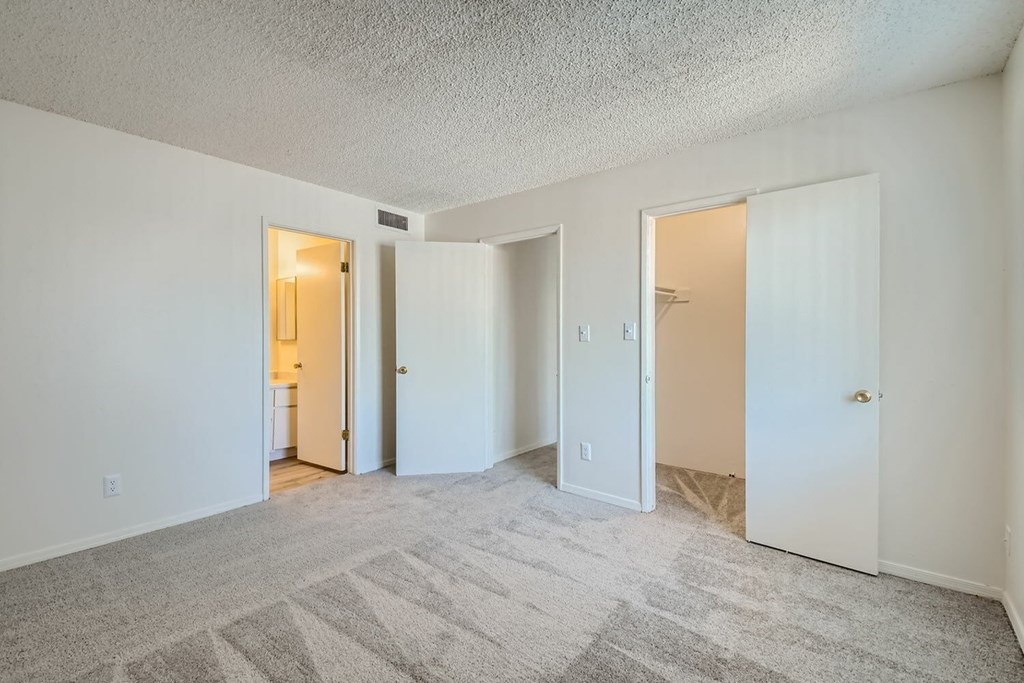 A spacious room with a carpeted floor and three doors.