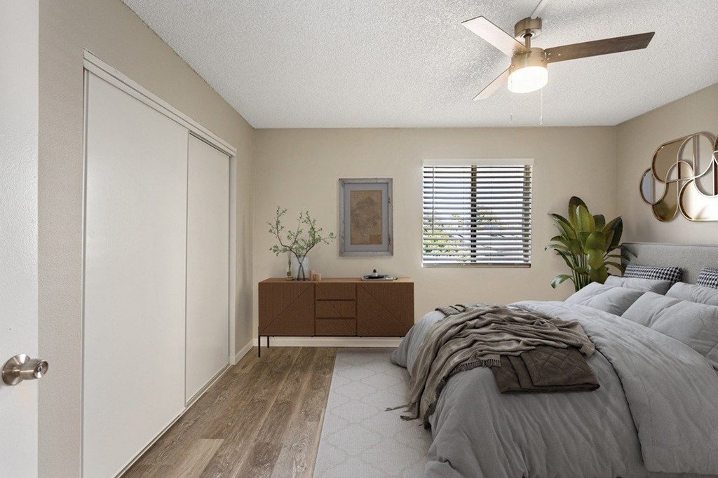 A bedroom with a bed, dresser, and a ceiling fan.