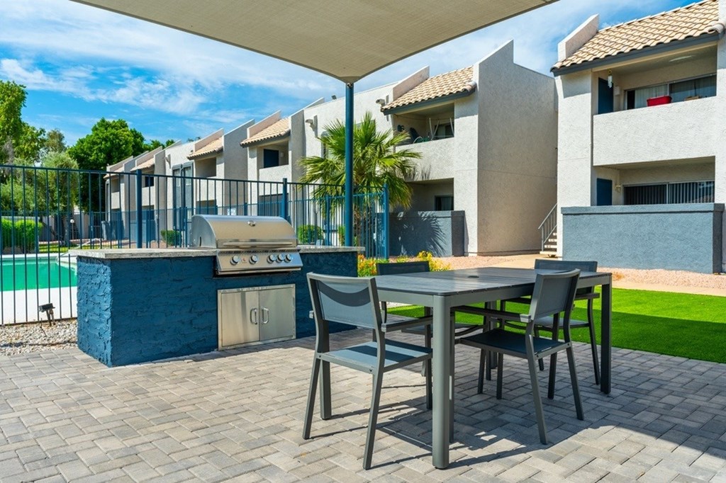 A patio with a table and chairs and a grill.