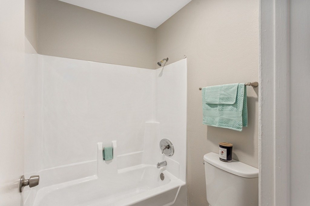 A white bathroom with a towel hanging on the wall.