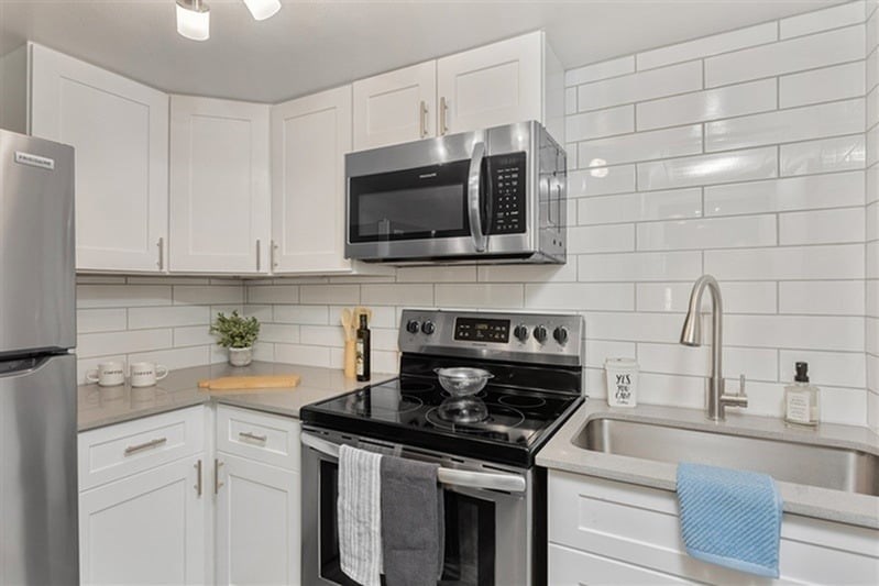 A kitchen with white cabinets and a black stove top.