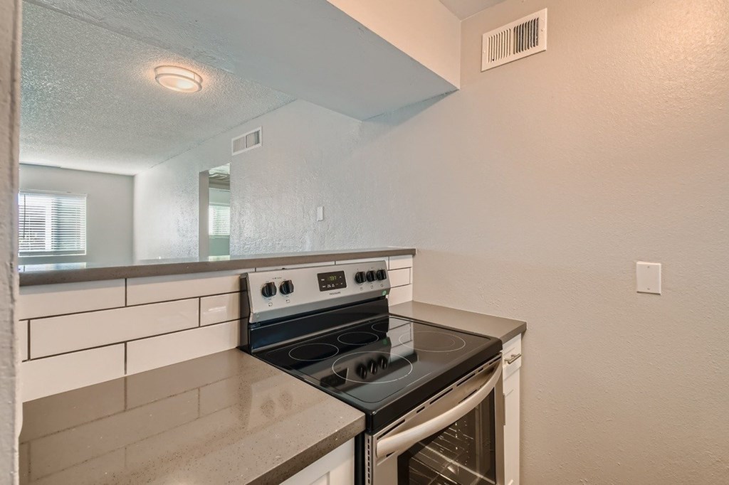 A kitchen with a stove top oven and a wall-mounted exhaust fan.