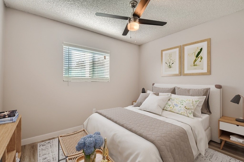 A bedroom with a bed, nightstand, and a ceiling fan.