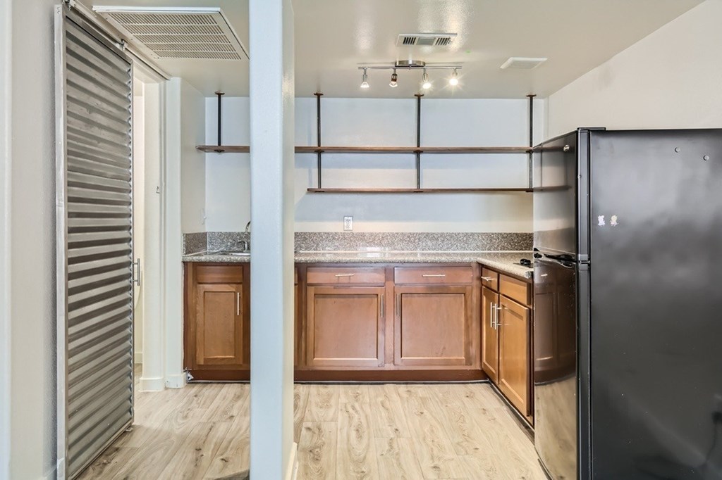 A kitchen with wooden cabinets and a black refrigerator.