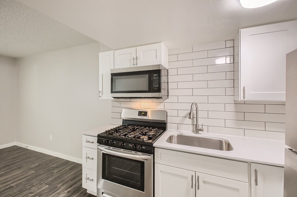 A kitchen with a stove, microwave, and oven.