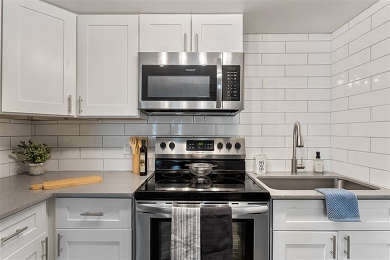 A modern kitchen with a stove top oven and microwave above it.
