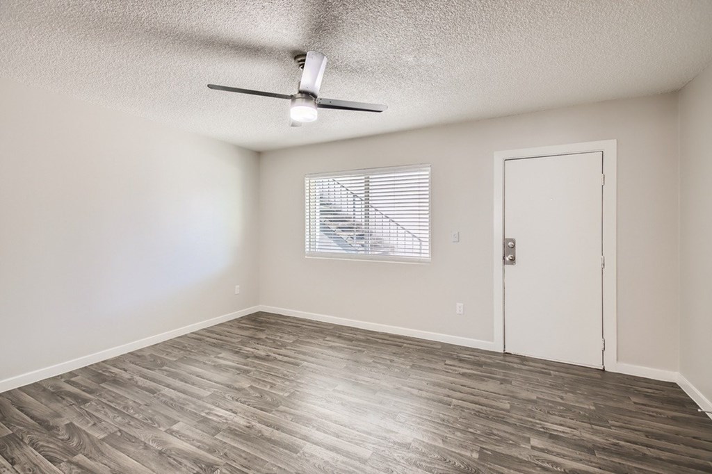 A room with a ceiling fan and a window with blinds.
