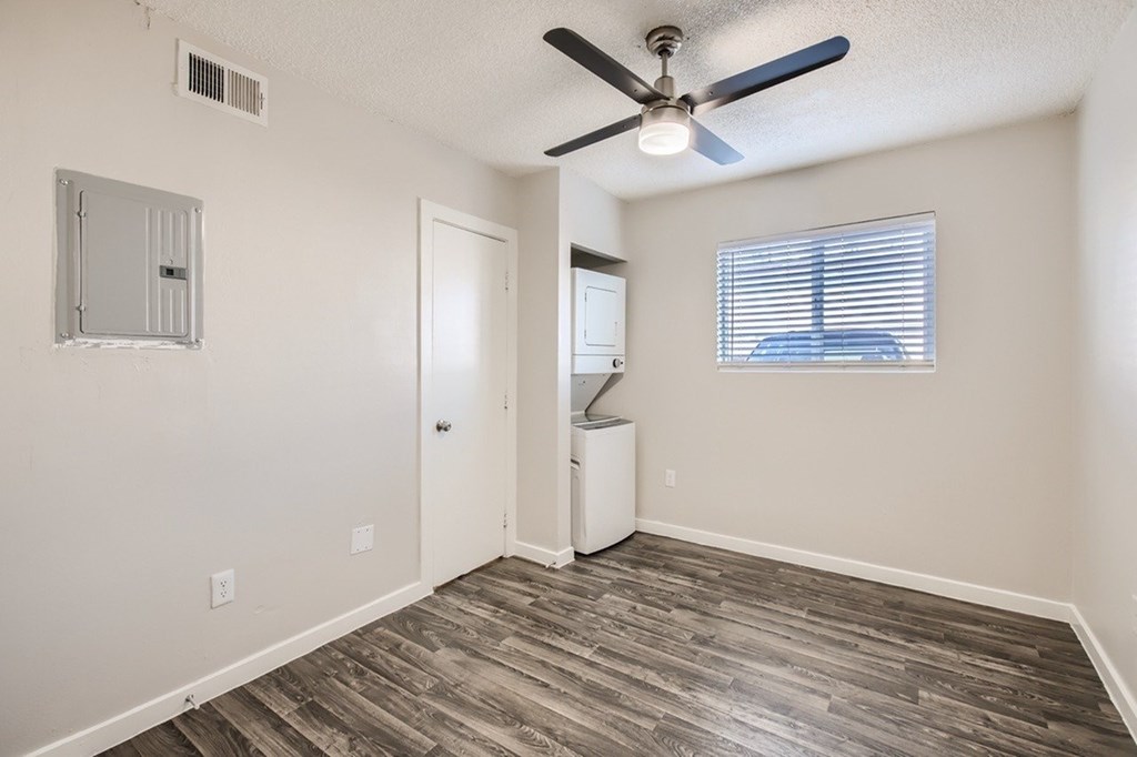 A room with a ceiling fan and a window with blinds.