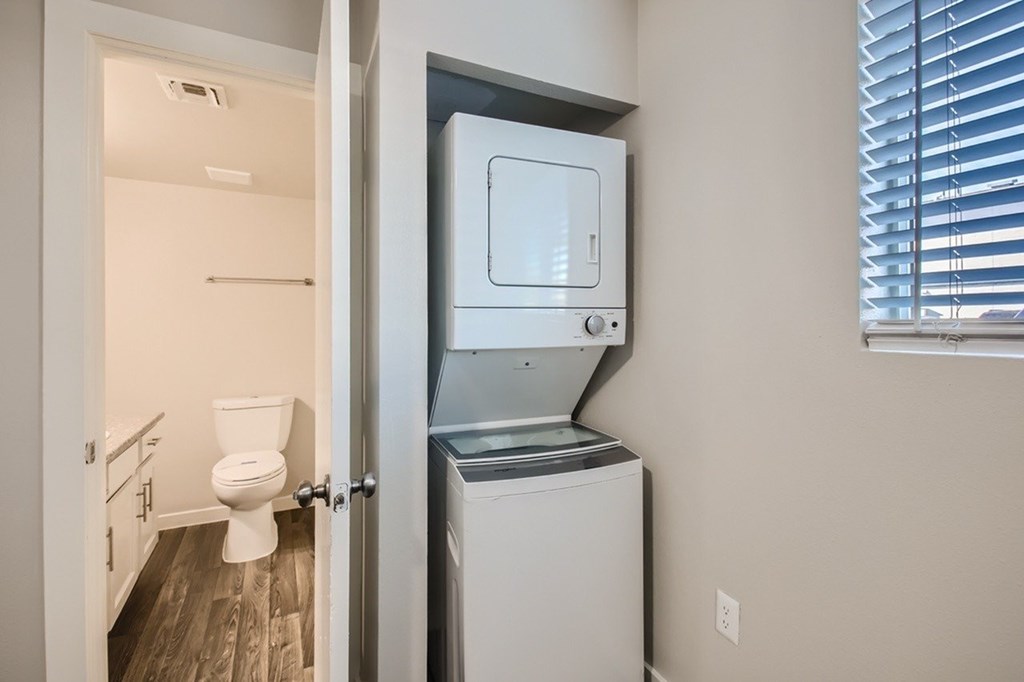 A white toilet is in a small room with a washer and dryer.