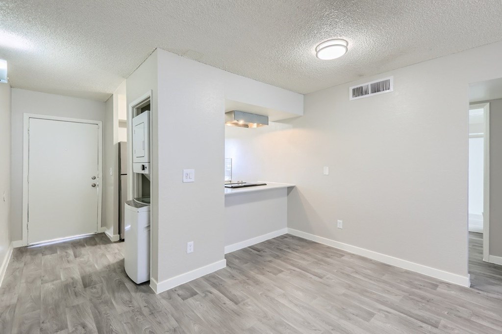 A white room with a kitchenette and a trash can.