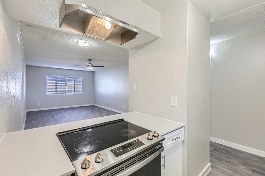 A kitchen with a stove top oven and a fan.