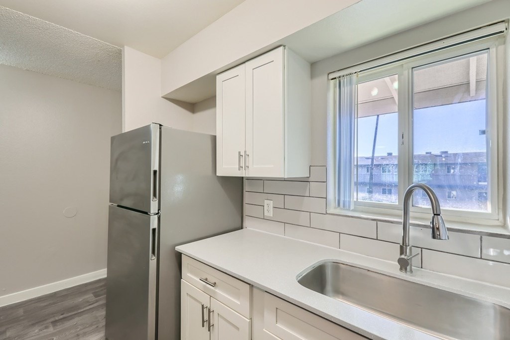 A kitchen with a stainless steel refrigerator and a white sink.