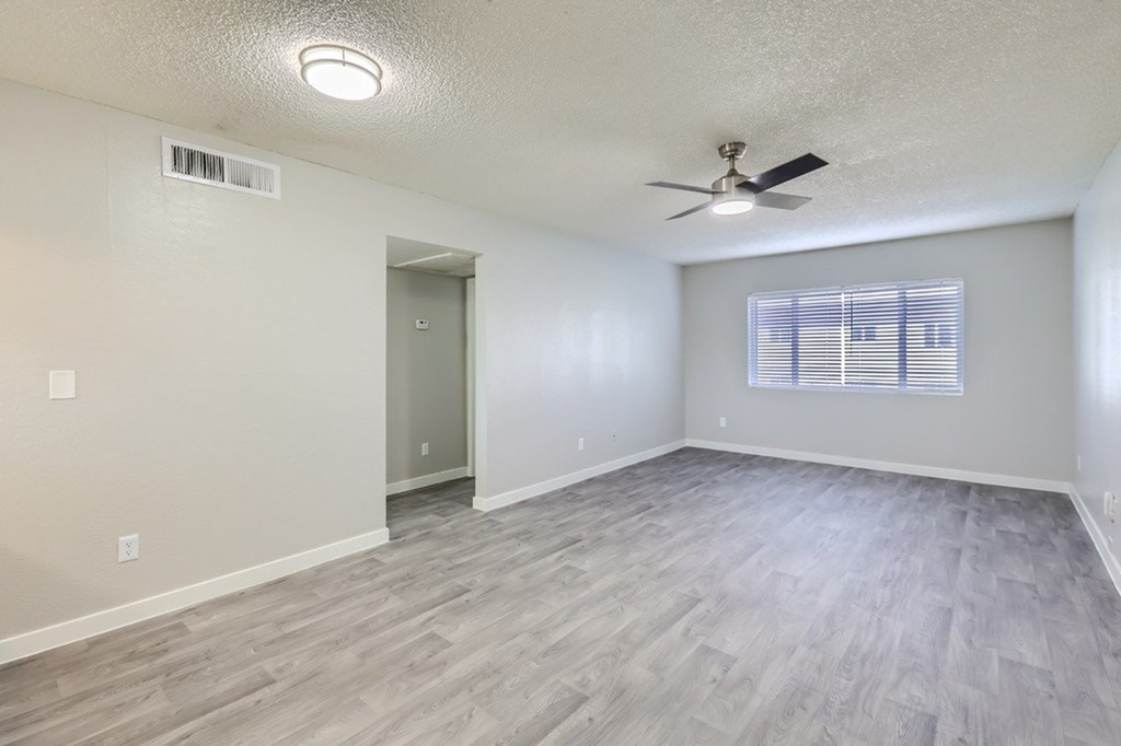 A room with a ceiling fan and light fixture, a door, and a window with blinds.